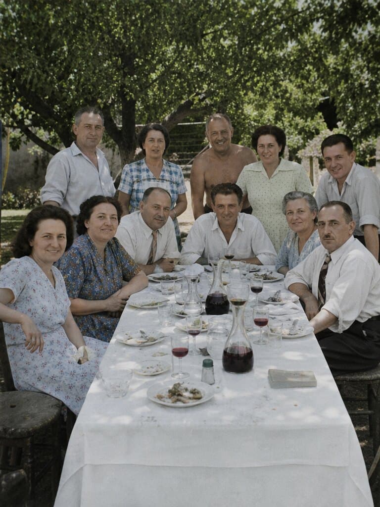 Onze personnes d’une même famille autour d’une longue table dressée au jardin, en 1954.