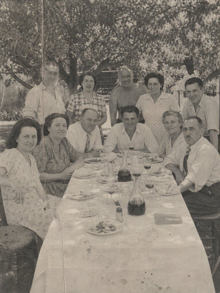 Onze personnes d’une même famille autour d’une longue table dressée au jardin, en 1954.